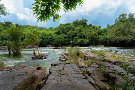 The water flowing over rocks and trees down a waterfall at Khao Ito waterfall , Prachin Buri in...