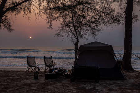 Traveling and camping concept - camp tent at night under a sky full of stars. Orange illuminated...