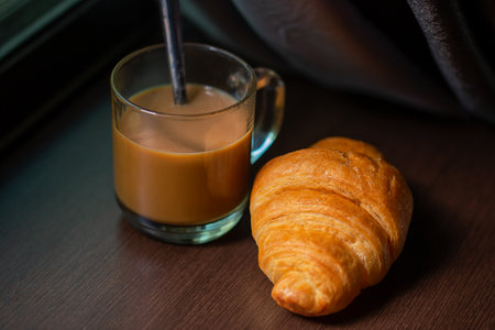 A cup of hot coffee and croissants on a wooden background. Breakfast with coffee and fresh pastry. Copy space. Freshの写真素材