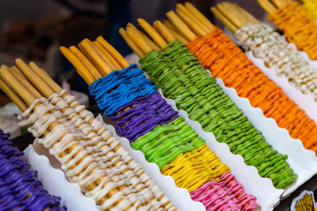 A snack made from long sticks of dough sprinkled with milk in various colors sold on the side of the...