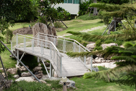 Old wooden white bridge over small pond or lake in city park. Concept of Asian garden design in summer timeの写真素材