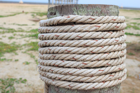 Close-up of a mooring rope with a knotted end tied around a cleat on a wooden pierの写真素材