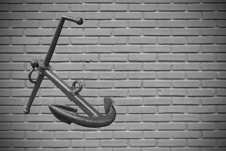 Vintage toned rusty boat anchor in the brick wall black and white .の写真素材