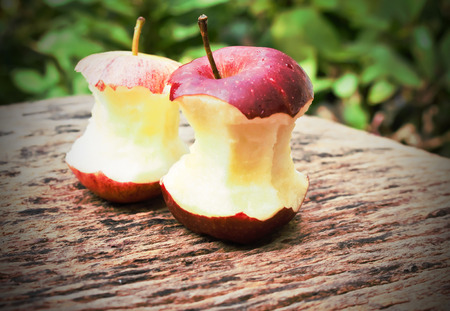 red apple eaten down to the core, on woodの写真素材