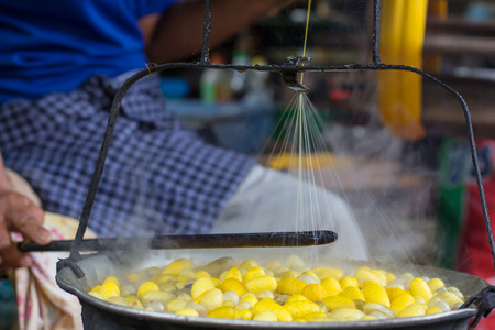 Thai woman boiling yellow silkworm cocoons and making silk thread. A traditional way of hand made silk production.の写真素材
