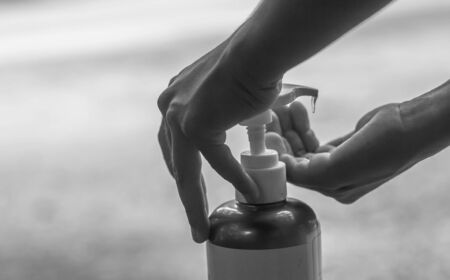 The boy's hand pressed an alcohol gel to wash his hands to prevent the virus in black and white.の写真素材