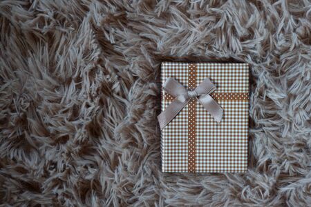 Gift box with a  ribbon and a Brown bow on a Wool carpet background. Selective focus.の写真素材