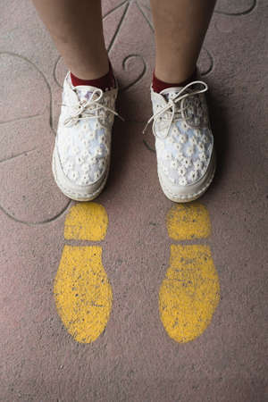 Feet and arrows on road. Yellow straight arrow sign and white shoes. Straight direction concept....