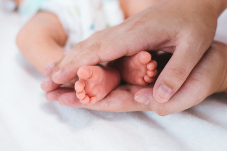 Newborn baby feet on white blanket. mother hold feets of newborn baby. Cmaternity and babyhood concept.の写真素材