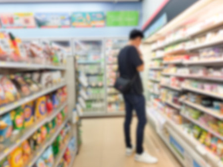 Blurred image of a man walking in a supermarket in a supermarket aisle with a back view of a man shopping in a department store.の写真素材