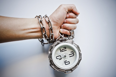 A hand chained with a clock の写真素材