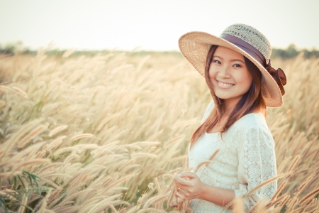 portrait of a young Asian girl standing in the middle of a golden grass field   expressing freedom   relaxationのeditorial素材