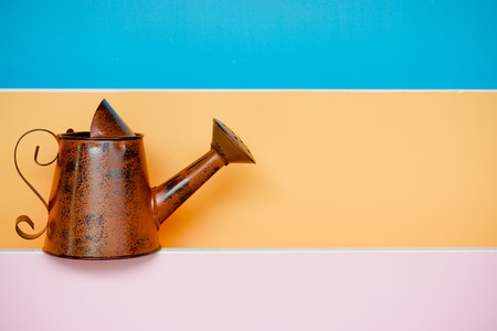 old and rusty watering can with colorful wood backgroundの写真素材