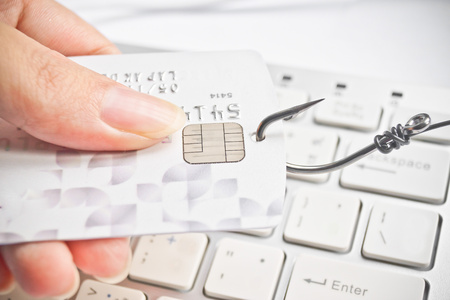 phishing - fish hook with a credit card on white computer keyboardの写真素材