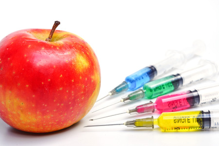 gmo apple surrounded by needles with chemical substancesの写真素材