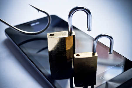 mobile phishing concept - a fish hook and metal locks on a smart phoneの写真素材
