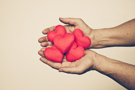 hand of the elderly female holding red hearts