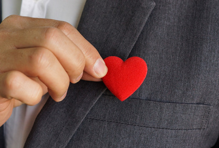 Businessman pulling out a red heart from the pocket of his suit - crm - service mindの写真素材