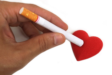 Cigarette burnt a red heart - smoking destroying health conceptの写真素材