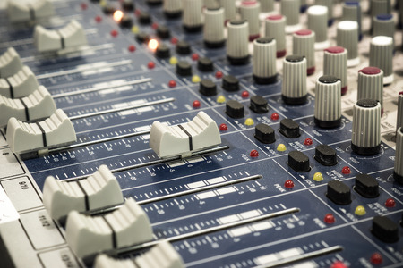audio mixing console with faders and adjusting knobs