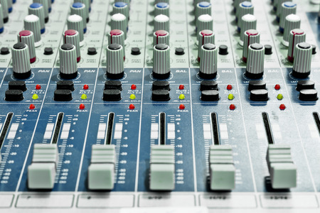 audio mixing console with faders and adjusting knobs