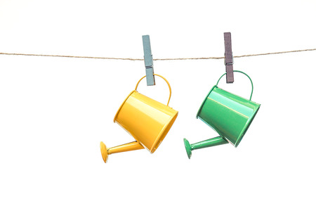 two green watering cans hung on the rope with red wooden clipsの写真素材