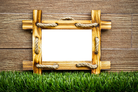old wooden picture frame with white space on green grass floor with wood backgroundの写真素材
