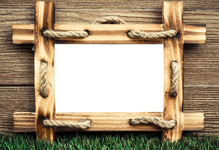 old wooden picture frame with white space on green grass floor with wood backgroundの写真素材