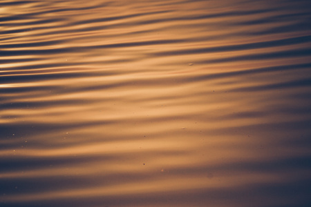 Abstract blur movement of water ripple surface waves with orange sunset lightの写真素材
