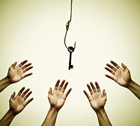 Many hands trying to get a key hung on a fish hook - the victim of successの写真素材