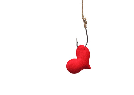a red heart with a fish hook - love trap conceptの写真素材