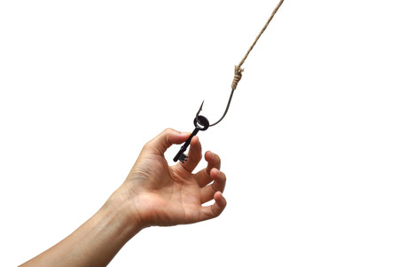 hand reaching out trying to get a key on a fish hook - The victim of success conceptの写真素材