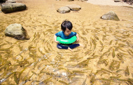Huay Luang waterfall, Ubon Ratchathani, Thailand - a boy playing in a clear water surrounded by many...