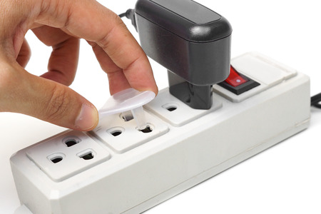 hand putting special equipment to cover plug holes of the surge protector - Preventing baby playing...