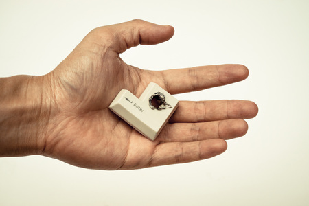 hacker's hand holding computer enter button with a hole  computer security breach conceptの写真素材