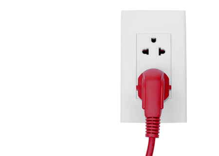 Red plug in a socket / Energy consumption conceptの写真素材