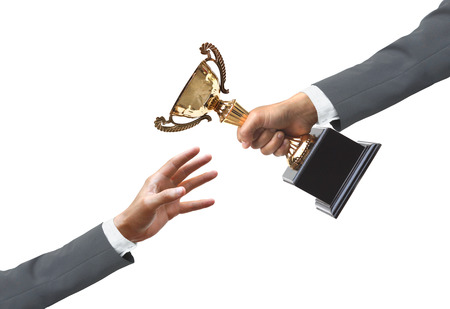 hand of a businessman giving a golden trophy to another businessmanの写真素材