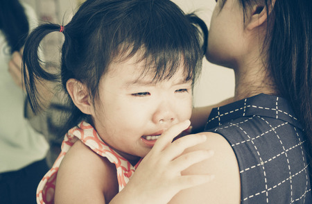 Asian baby girl hugging her mother cryingの写真素材