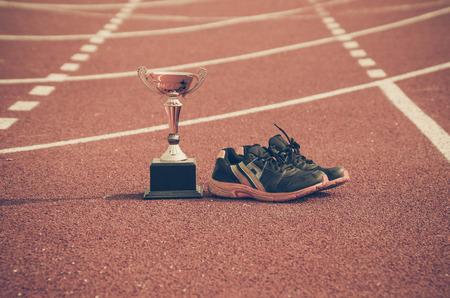 A golden trophy and running shoes on running race laneの写真素材