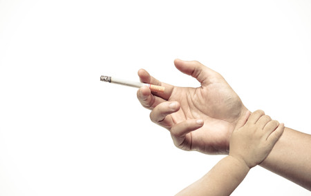 Stop smoking. Hand of a baby touching hand of a father with a cigarette. Dad stop smoking concept.の写真素材