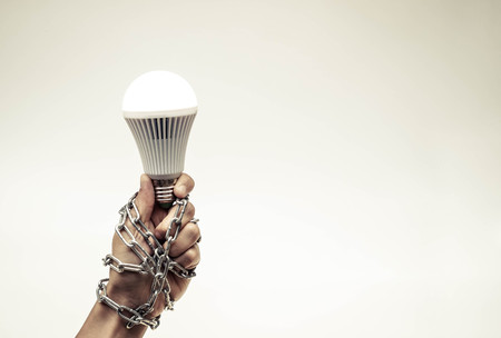 A turned on LED light bulb chained and lock / Something stops new ideaの写真素材