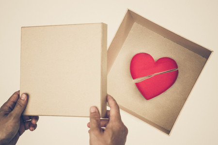 Hand open a paper box with a broken red heart inside / Ending relationship conceptの写真素材