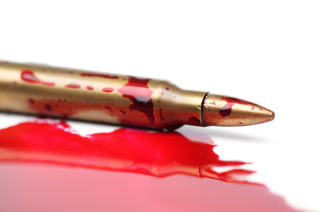 A rifle bullet with red blood / Bloodshed business / selling weapons causing deathの写真素材