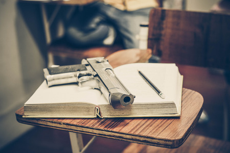 A gun on a textbook / Armed campus concept