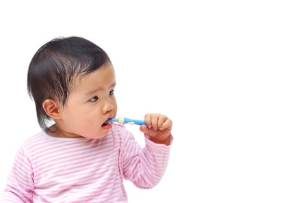 a young Asian baby brushing teeth isolated on whiteの写真素材