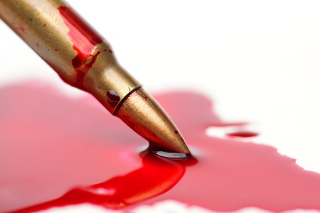 A rifle bullet with red blood / Bloodshed business / selling weapons causing deathの写真素材