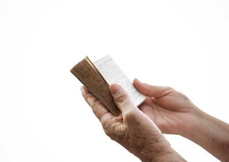 Old female hand holding an old small book of bible