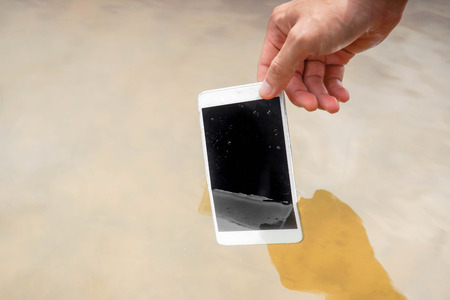 Hand holding a wet smartphone / Waterproof smartphone conceptの写真素材