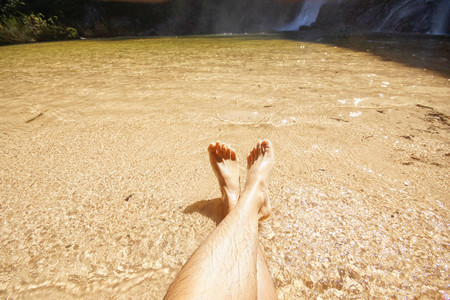Two feet dipping in a clear water of a stream in sunny weather / Vacation conceptの写真素材