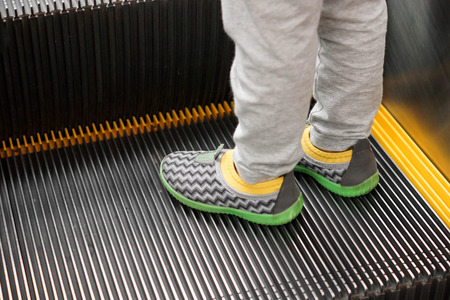 Kid standing alone on escalatorの写真素材